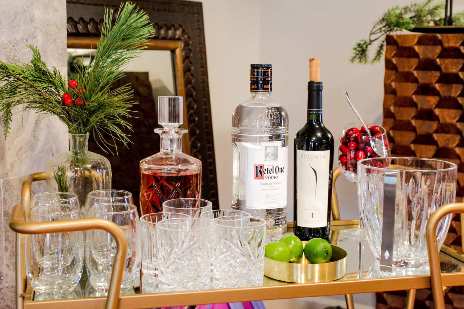 A bar cart holding decanters, bottles and glassware