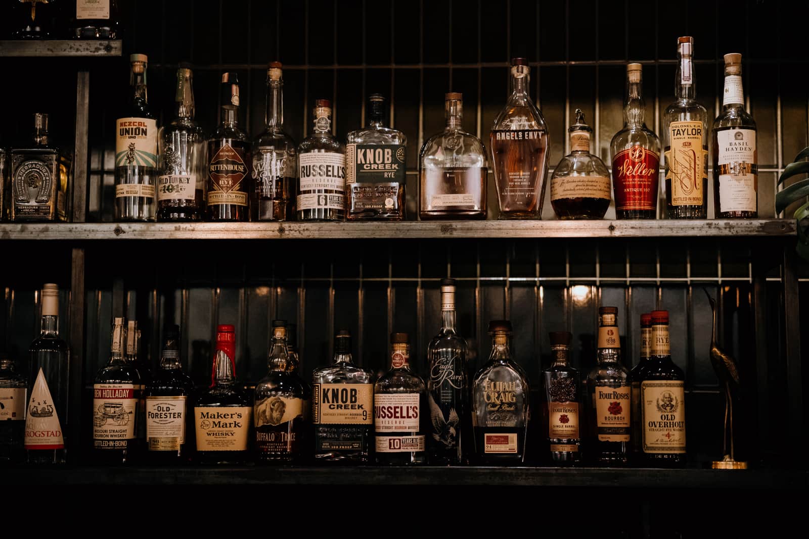 A collection of whiskey bottles on wooden shelves