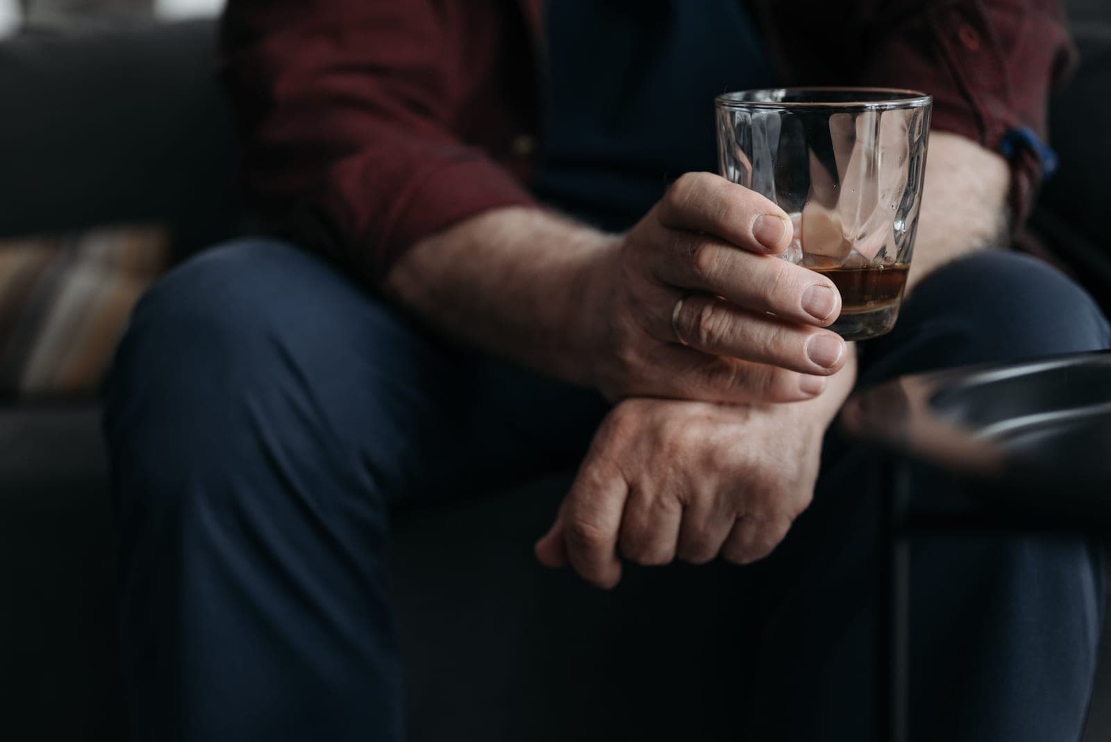 A man holding a glass of whiskey in warm light