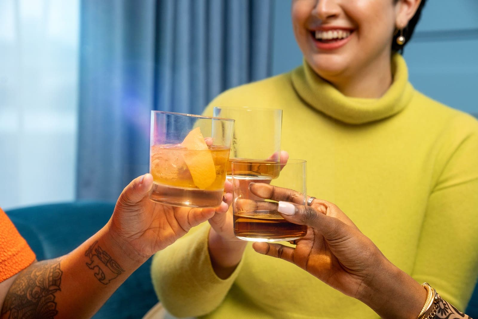Two people touching whiskey glasses in a toast