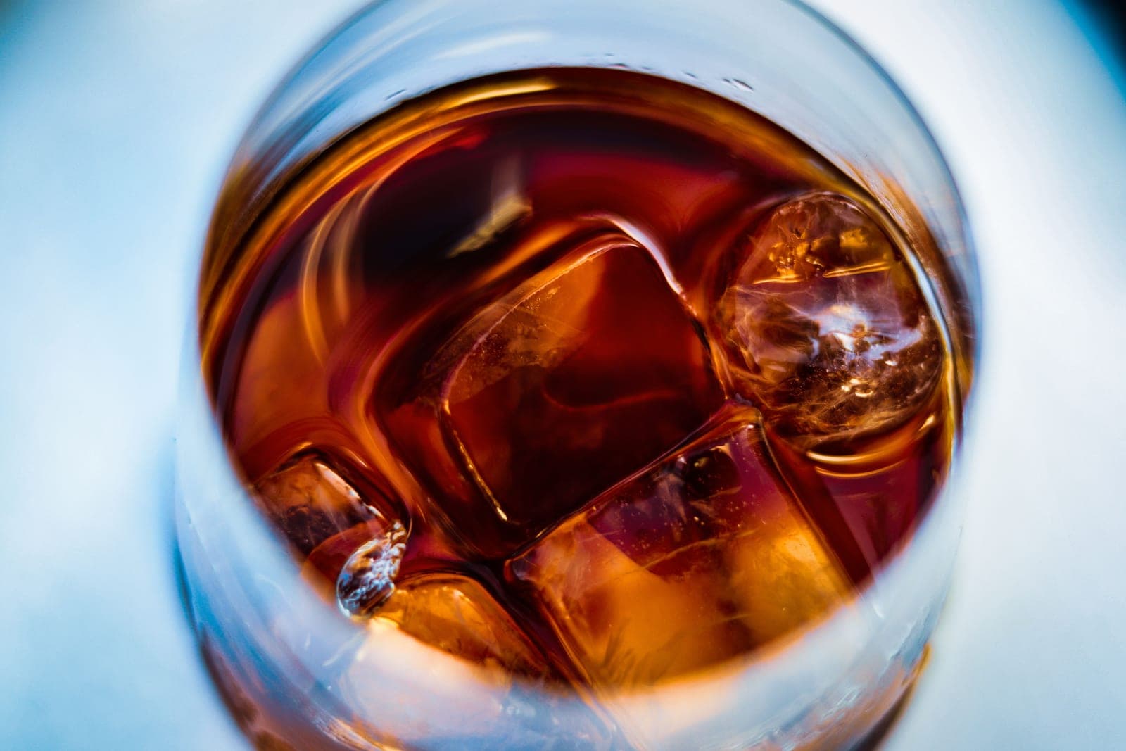 A close-up of whiskey served over ice in a heavy tumbler