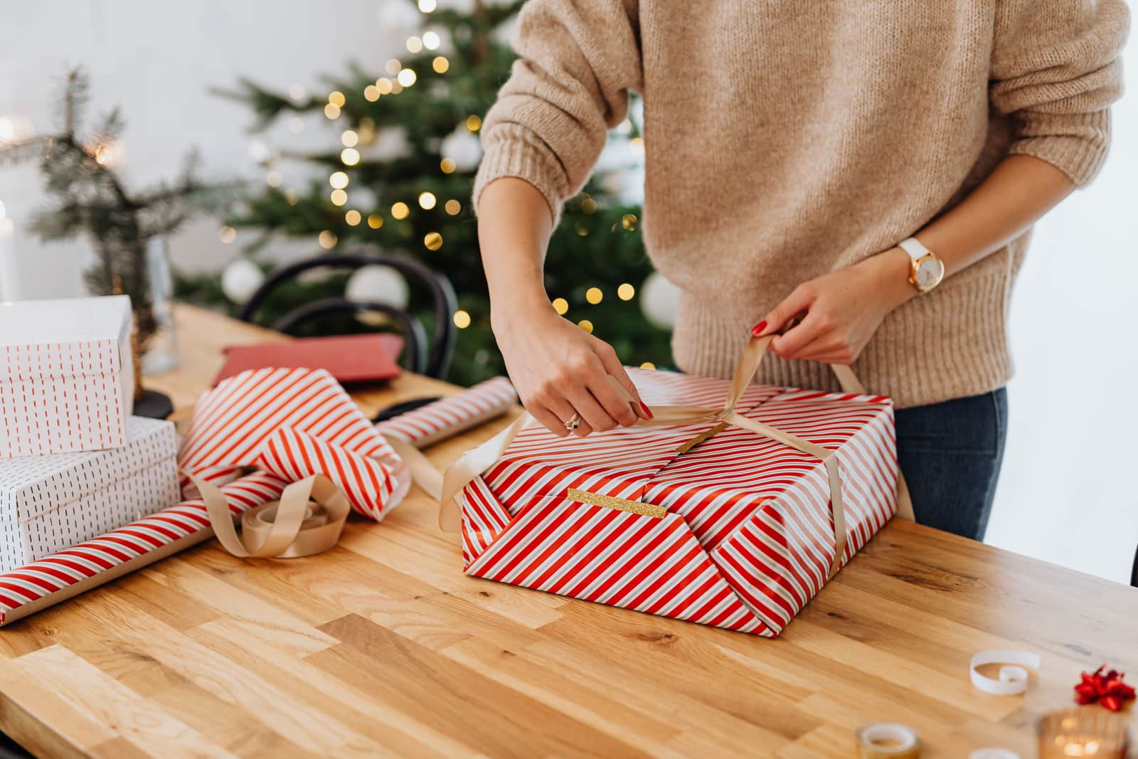 Wrapping a gift in paper with twine on a wooden table